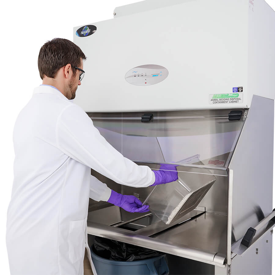 User dumping animal bedding into a refuse receptacle in an Animal Waste Workstation.