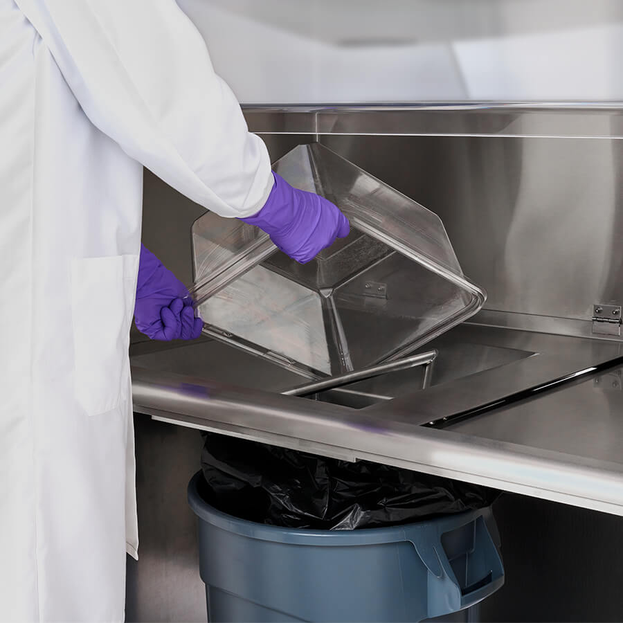 Animal technical dumping animal waste from a cage in a NU-608 Animal Refuse Workstation.